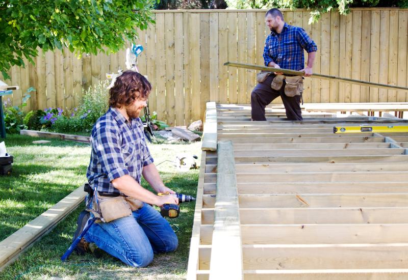 Two men constructing a wooden deck, focused on their work in Annapolis, MD