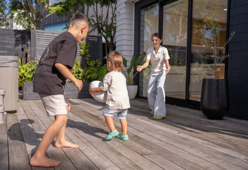 In Annapolis, MD, three children are playing on a deck, surrounded by a cheerful outdoor atmosphere.