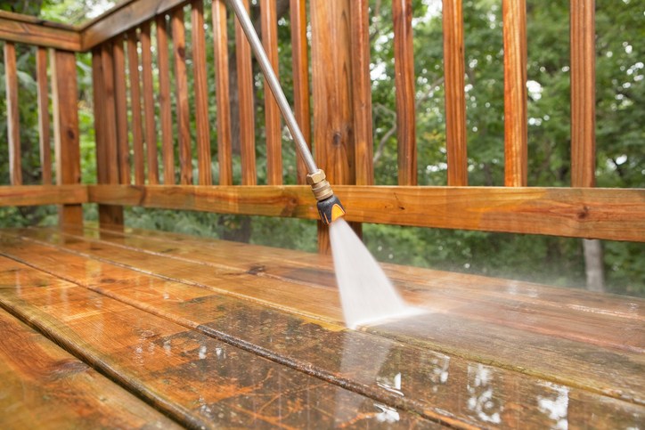 A professional operates a pressure washer to clean a wooden deck at a residence in Annapolis, MD