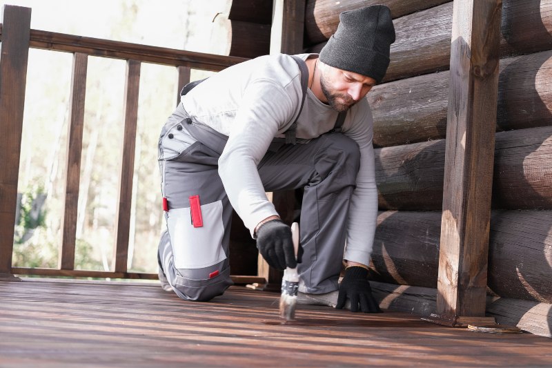 A man wearing protective gloves focuses on detailed deck restoration work in Annapolis, MD