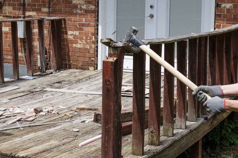A Professional Uses a Hammer to Remove Damaged Wood from a Deck Structure in Annapolis, MD